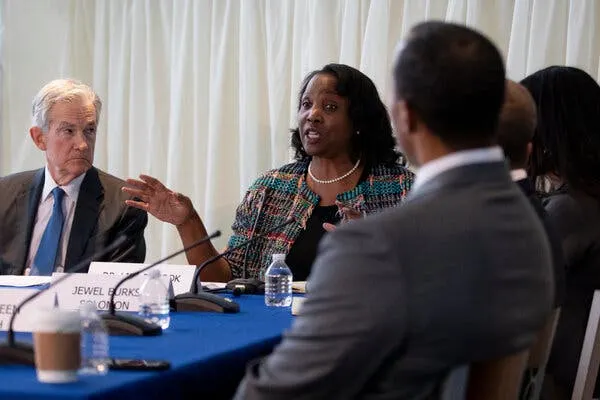 Lisa Cook sits at a table and talks into a microphone in 2023 in Atlanta. 